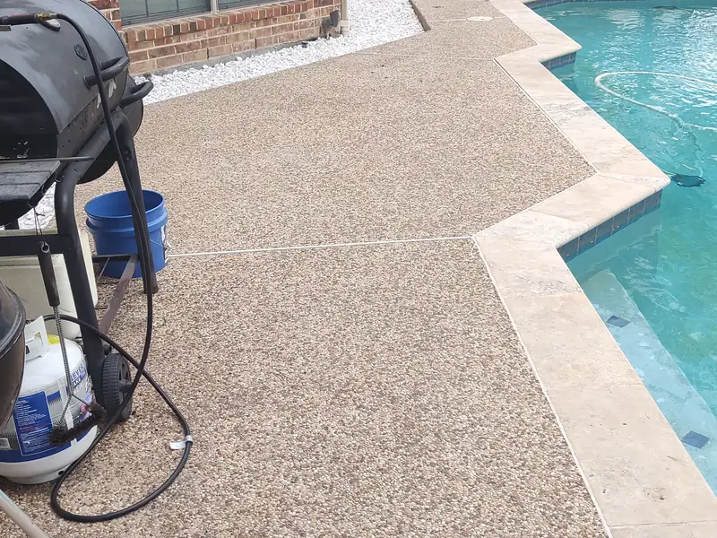 Exposed-aggregate pool deck and travertine coping with control joints, checked for movement and settlement